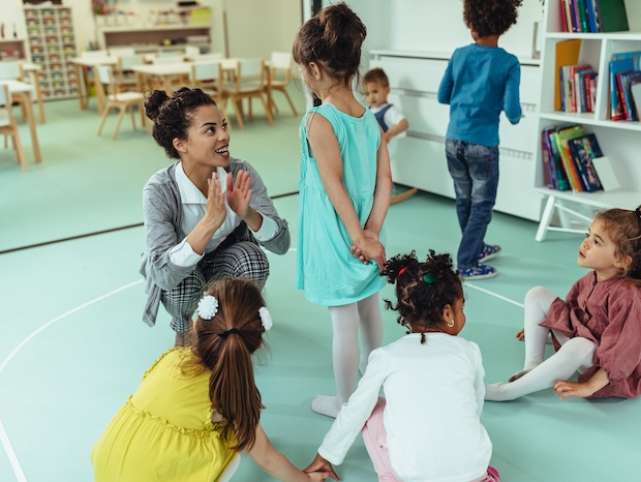 Teacher is playing with cheerful children at kindergarten